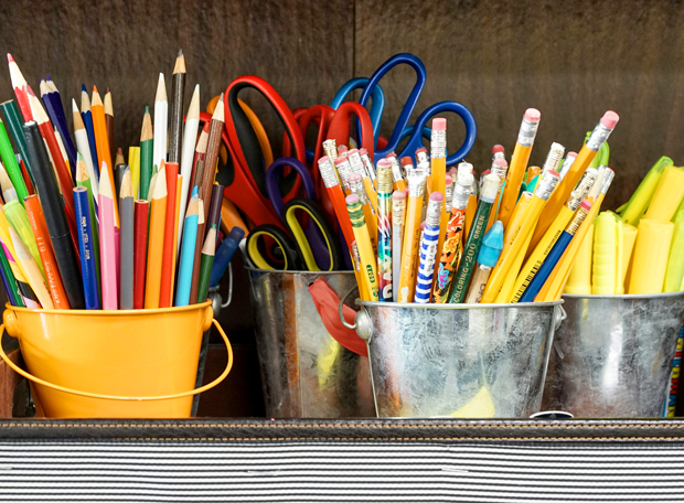 Bunte Stifte, Scheren und Textmarker in Metall- und Kunststoffbehältern im Klassenzimmer